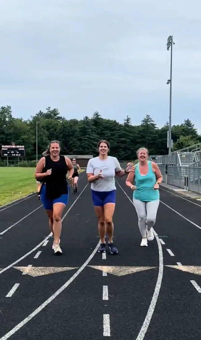 Three community-workout participants running on a track